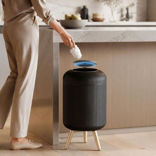 poubelle design automatique noir s'ouvrant devant une personne en cuisine