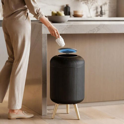 poubelle design automatique noir s'ouvrant devant une personne en cuisine