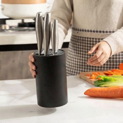 femme dépose porte couteaux cuisine sur plan travail légumes devant