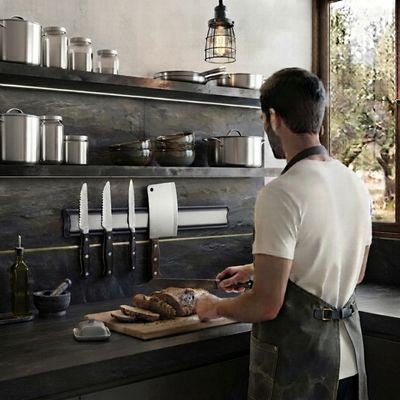 homme tranche pain sur planche barre aimantée pour couteaux devant