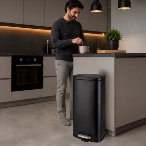 Poubelle à pédale noire inox homme proche prend son café