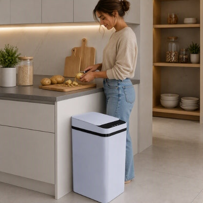 poubelle automatique blanche à côté d'une femme préparant le repas