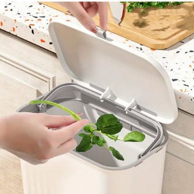 main jette déchets dans poubelle cuisine sous évier