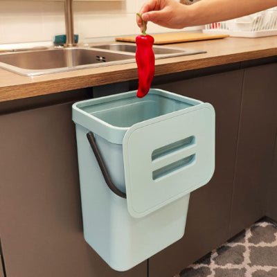 Poubelle sous évier bleue recevant poivron rouge depuis plan travail