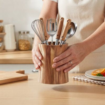 une personne dépose pot ustensiles cuisine sur comptoir