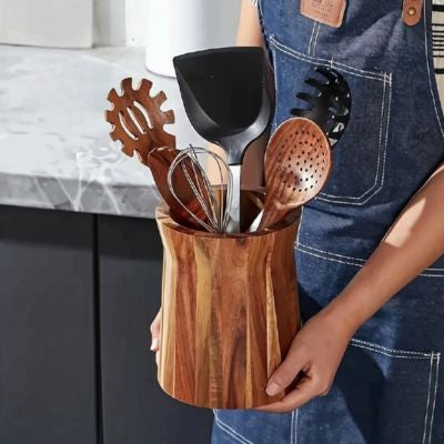 une personne porte pot ustensiles cuisine en bois avec ustensiles